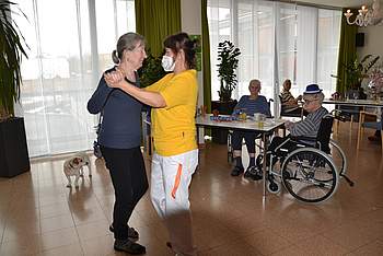 Bewohnerin und Betreuerin tanzen miteinander