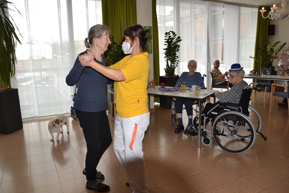 Bewohnerin und Betreuerin tanzen miteinander