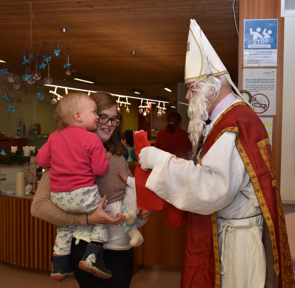 Der Nikolaus verteilt Sackerl an kleines Kind.