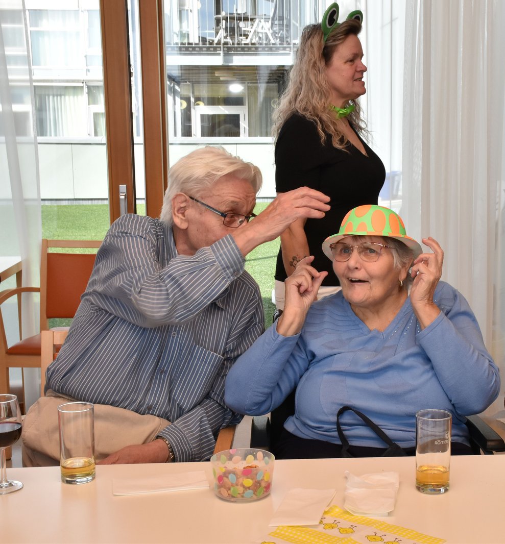 Herr Stark setzt Frau Dafert den Hut auf.