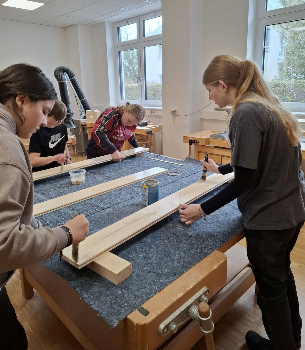 Drei Schülerinnen bemalen die Balken.