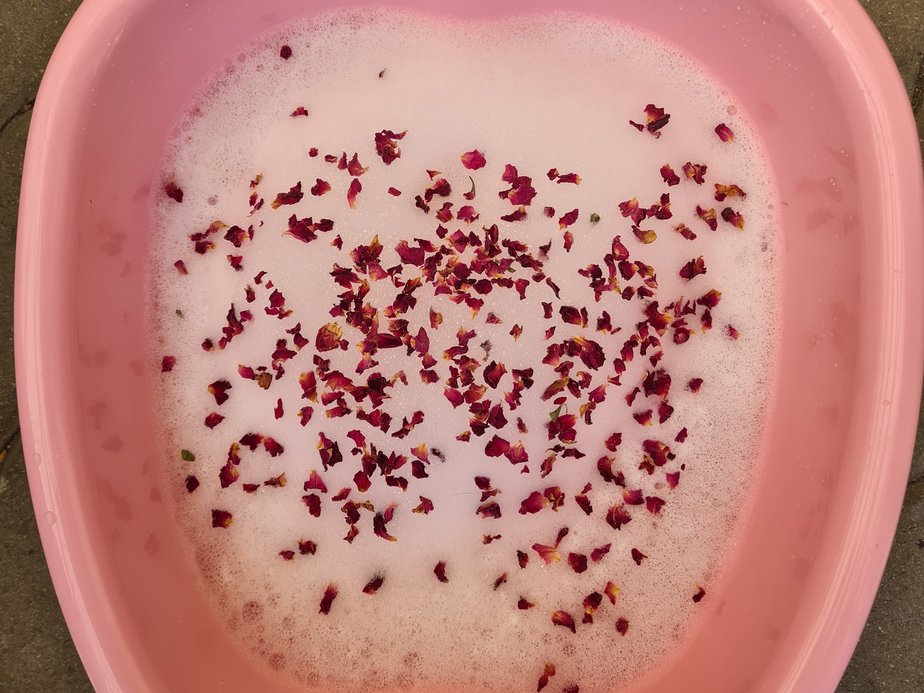 Eine Wanne, die mit Schaum und Blüten gefüllt ist.