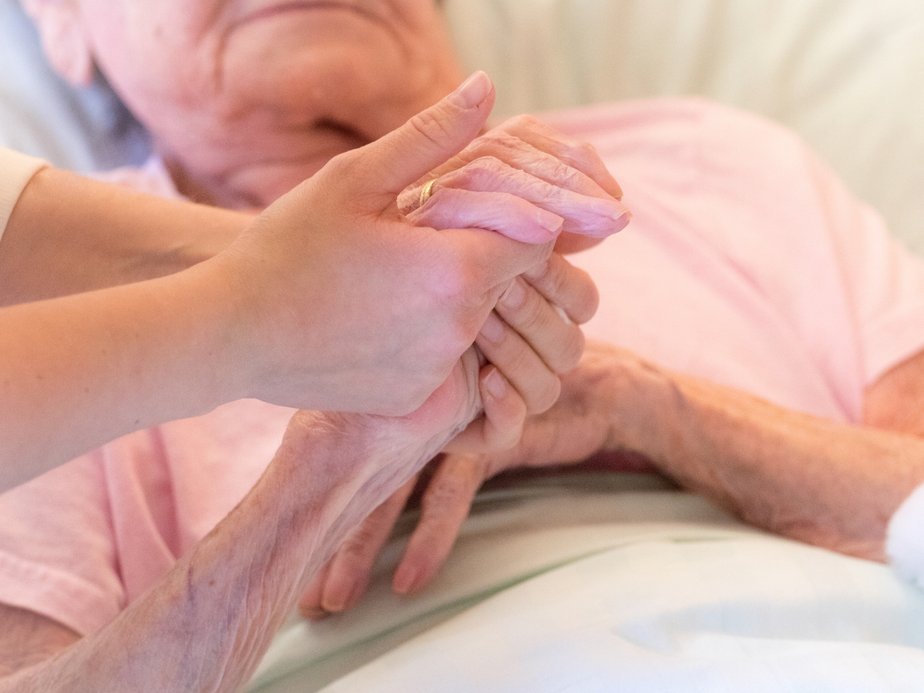 Betreuerin hält Hand einer Bewohnerin.