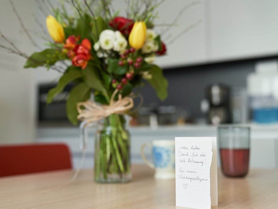 Ein Blumenstrauß und eine Karte stehen auf einem Tisch.