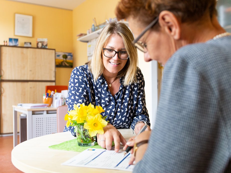 Zwei Frauen sitzen bei einem Tisch.