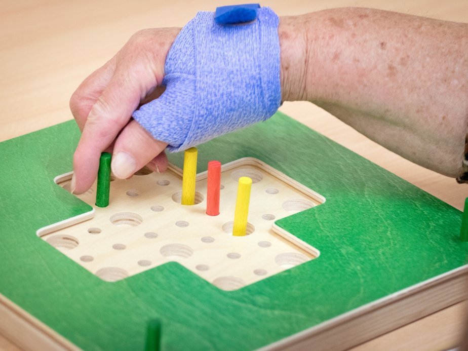 Bewohnerin hält Holzstäbe.