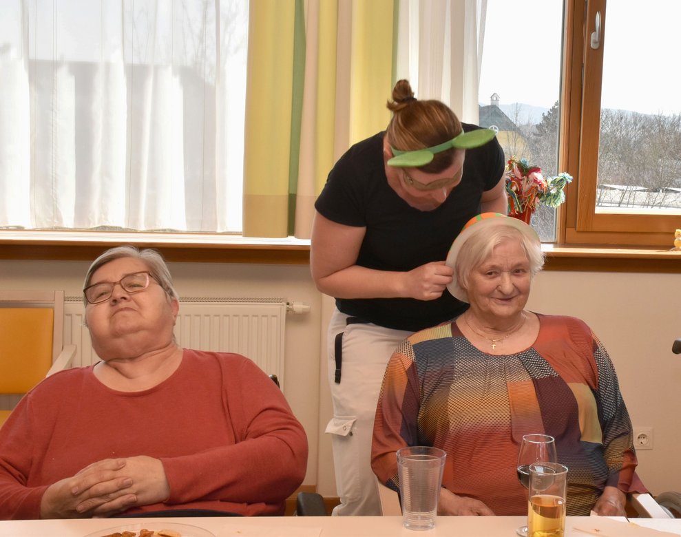 Karin Steiger setzt Frau Widhalm einen Hut für das Hut-Spiel auf.